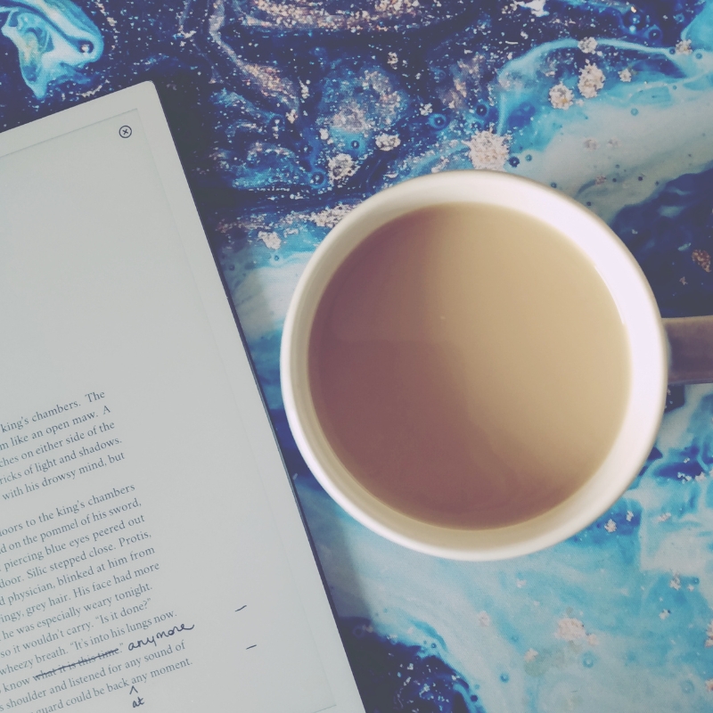 Mug of tea beside writing tablet on blue background